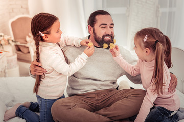 Joyful happy girls decorating their dads beard