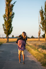 Enjoying beautiful day. Rear view of young cheerful man carrying his beautiful girlfriend on shoulder