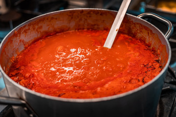 Traditional famous Italian tomato sauce for any kind of pasta, local name for this dish is "sugo". Slow flame cooking, rich red bubbles in steel kitchen. Mediterranean style and nutrition habits. 