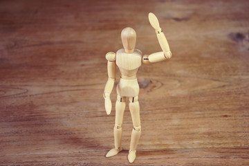 Wooden model showing dramatical pose on darker wooden table background