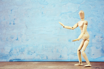 Wooden model showing dramatical pose in front of blue art background