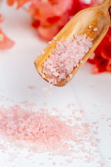 Pink sea salt dripping from a wooden spoon.
