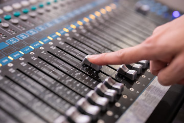 Hand using sound music mixer control panel in the event hall