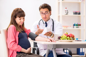 Obraz premium Pregnant woman visiting doctor discussing healthy diet
