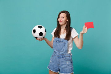 Confused puzzled young woman football fan support team with soccer ball, red card propose player retire from field isolated on blue turquoise background. People emotions, sport family leisure concept.