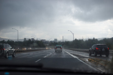 Fototapeta na wymiar Cars are driving along the highway in rainy foggy weather to the city, which stands among the mountains. Asheville, North Carolina / USA, July 07/2018