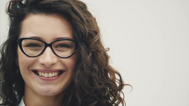 Young pretty girl with gorgeous hair. On a white background. Dressed in glasses sincerely smiles.