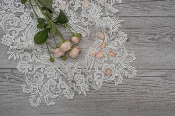 White wooden background with white spring flowers roses and lace ribbon. Happy womans day. The texture of lace on wooden background.