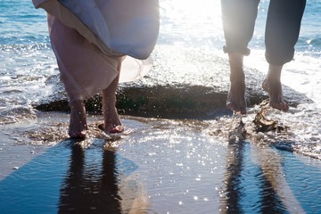 Couple of heterosexual couple having fun splashing waves on the beach.