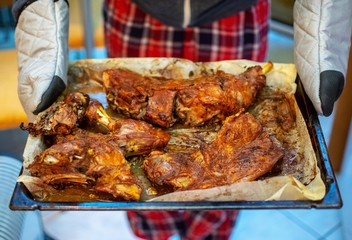 A person holds a pan with fresh grilled lamb steaks at a kitchen.
