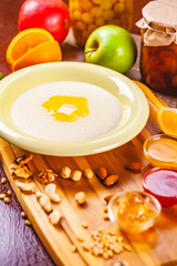 Semolina porridge with nuts, jam and fruits on wooden board
