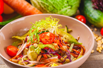 Vegetable salad with pine nuts in beige bowl