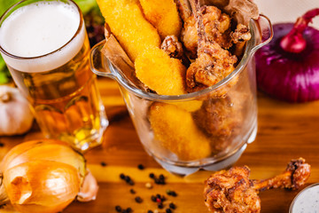 Fish fingers and fried chicken in glass bowl served with beer