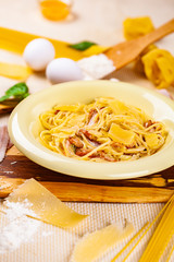 Spaghetti carbonara with bacon and parmesan cheese in beige plate