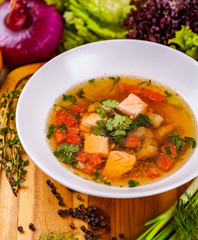 Soup with salmon, vegetables and spices in white plate