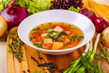 Soup with salmon, vegetables and spices in white plate