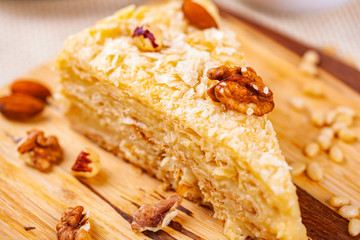 Napoleon cake with different nuts on wooden board