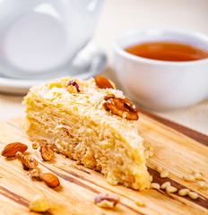 Napoleon cake with different nuts on wooden board