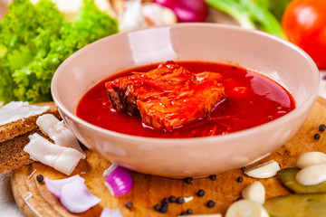 Borscht with vegetables and meat in pink plate. Ukrainian cuisine