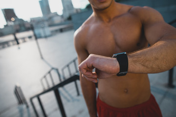 Bare-chested male watching at digital device outside