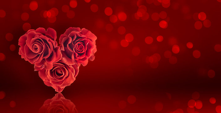 Card for Valentines Day with roses bouquet in the shape of heart on a red background with glowing bokeh
