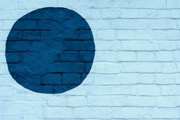 Drawn painted dark blue circle on light blue brick wall bricks surface of wall, as graffiti. Graphic grunge texture. Abstract background, stylish pattern
