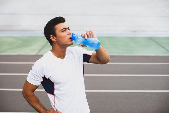 Focused male tasting beverage after workout outdoor