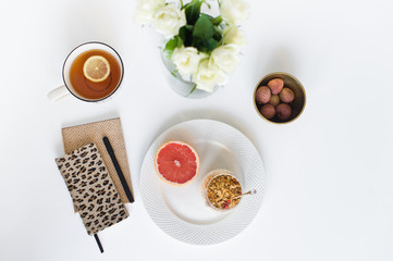 Obraz na płótnie Canvas Healthy business Breakfast. Ingredients: grapefruit, granola, yogurt, lychee, tea. Diaries on the table. Top view, white background.