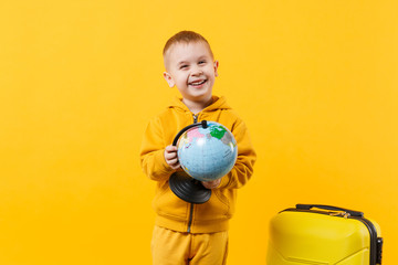 Little traveler tourist kid boy 3-4 years old isolated on yellow orange wall background studio. Passenger traveling abroad to travel on weekends getaway. Air flight journey concept. Mock up copy space