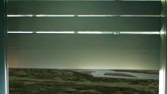 Opening Old Wooden Roller Shutters on Window of a Room discovering a Landscape of Hills, Mountains and Beaches in the Falkland Islands (Islas Malvinas), South Atlantic.