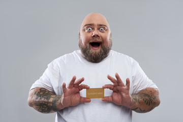 Funny bearded man feeling excited while holding gold card