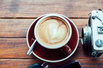 Top view Cup of hot coffee , film camera smartphone and key on the wood plate