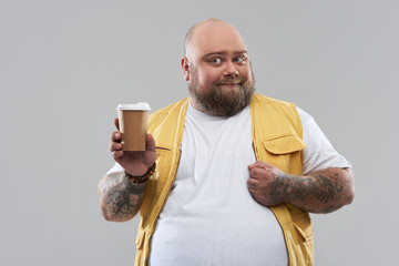 Funny bearded fat man showing glass of coffee and smiling