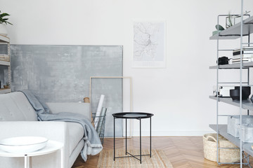Stylish nordic home interior with grey bookstand with accessories, design sofa , coffee table and stylish furniture. Empty white walls. Cozy space of living room. Brown wooden parquet