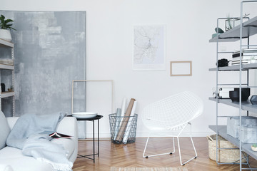 Scandinavian home interior with grey bookstand with accessories, design grey sofa, coffee table and...