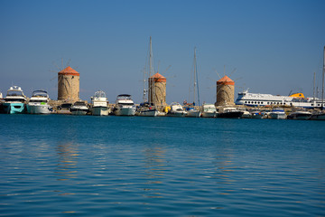 Fototapeta premium The windmills,fort of St Nikolas,Church of the Assumption and the Governors palace are on Rhodes Mandraki Harbour 