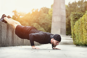 Healthy lifestyle concept. Muscular athlete exercising push up outside in city park.