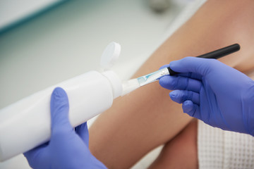 Highly qualified aesthetician preparing gel for laser hair removal treatment