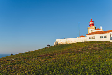 Fototapeta na wymiar Cape Roca lighthouse (Cabo da Roca). Green grass, blue sky and atlantic ocean, Westernmost Europe.