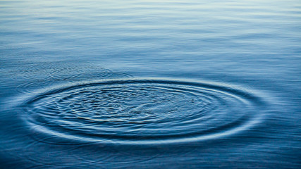 Ripples on sea texture pattern background. Round droplets of water over circles on pool water....