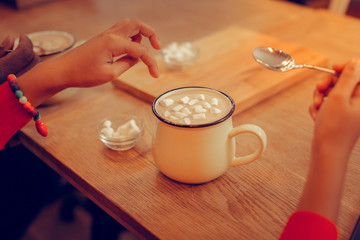 Little girl wearing bracelet getting warm in cafe drinking cocoa