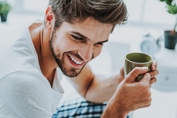 Smiling young guy drink coffee in morning