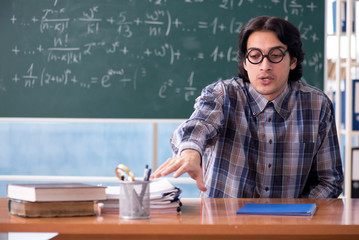 Young funny math teacher in front of chalkboard 