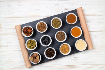 Various spices in bowls on a black slate board. Spices background. Top view