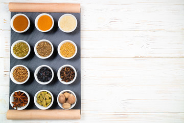 Various spices in bowls on a black slate board. Spices background. Top view, copyspace