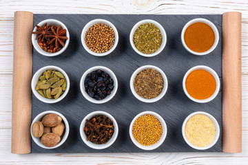 Various spices in bowls on a black slate board. Spices background. Top view