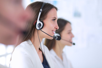 Smiling businesswoman or helpline operator with headset and computer at office