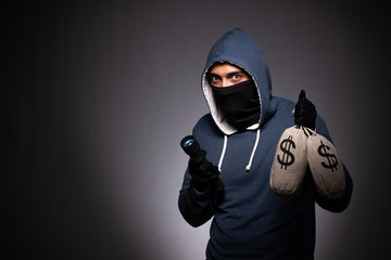 Young gangster in hood on grey background 