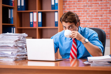 Young employee with excessive work sitting at the office 