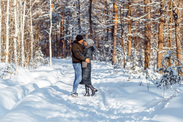 Fototapeta na wymiar A happy couple with a dog (black Labrador) having fun outside in the forest on a sunny frosty winer day.
